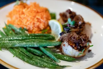 Seared scallops under a crumbled bacon and onion topping, with green beans and tomato rice