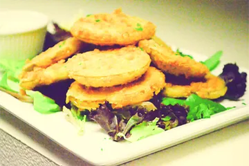 Fried green tomatoes stacked on a bed of mixed greens