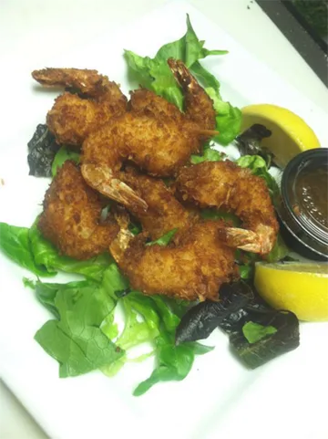 Golden fried coconut shrimp with lemon wedges and dipping sauce